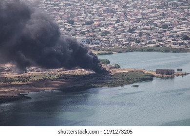 High angle view of smoke spreading from building. Arson of industrial warehouse, big smoke cloud spreading with wind. Massive damage on company building or warehouse engulfed in raging fire