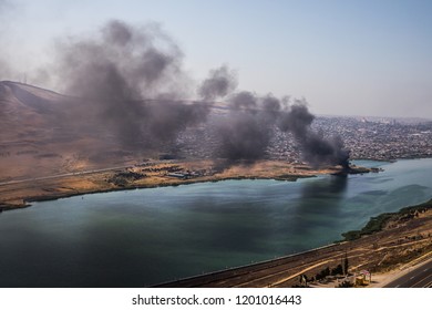 High angle view of smoke spreading from building. Arson of industrial warehouse, big smoke cloud spreading with wind. Massive damage on company building or warehouse engulfed in raging fire