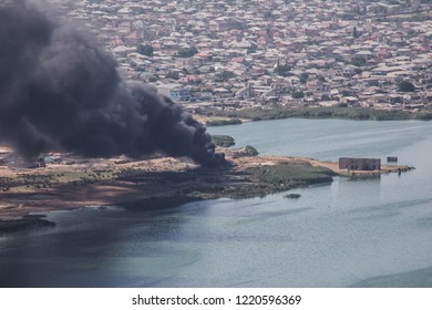 High angle view of smoke spreading from building. Arson of industrial warehouse, big smoke cloud spreading with wind. Massive damage on company building or warehouse engulfed in raging fire