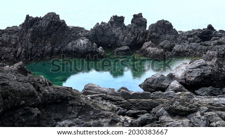 High angle view of Socheonji Pond at the center of volcanic rocks on the sea near Seogwipo-si, Jeju-do, South Korea 
