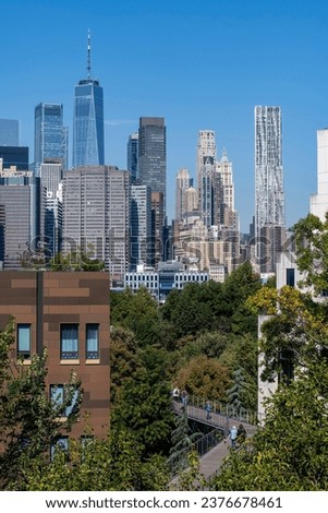 High angle view of Squibb Park Bridge in Brooklyn Bridge Park, Brooklyn Heights, New York City, NY, USA with panoramic view of skyscrapers and landmarks of Lower Manhattan against a clear blue sky