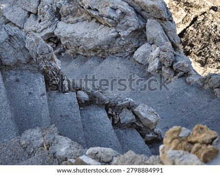 High angle view of steep stone stairs winding down through rugged natural rocks and cliffs on a sunny day in Petrovac, Montenegro