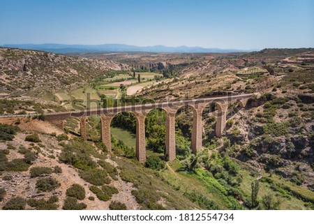 High angle view, stone bridge spans over a green valley on sunlight. Ojos negros green way in Albentosa, Teruel, Spain.