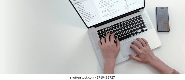 High angle view of student hands typing on laptop computer displaying algebra problems next to smartphone calculator app on white table with large empty space for text or design placement
