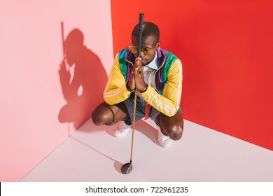 high angle view of stylish african american man with golf club crouching in studio - Shutterstock ID 722961235