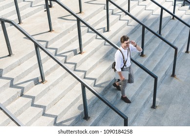 High Angle View Of Stylish Young Man Walking On Stairs With Laptop On City Street