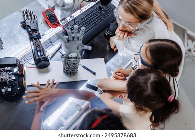 High angle view of teacher helping to girls working on small robot, building robotic kit in after-school robotics club. Children learning robotics in Elementary school. Girls in science. - Powered by Shutterstock