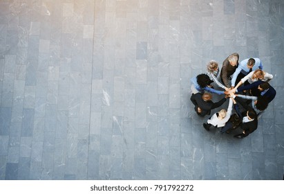 High angle view of a team of united businesspeople standing with their hands together in a huddle in the lobby of a modern office building