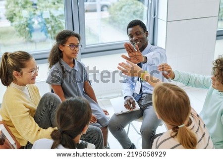 High angle view of teen high five with therapist while celebrating success in support group circle