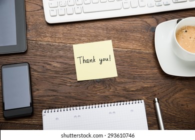 High Angle View Of Text Thank You On Post Note At Wooden Desk