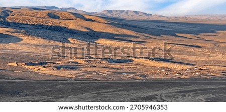 High angle view of Thacker Pass in Nevada, USA, shows an expansive lithium mine. The landscape is vast with earthy tones, featuring excavation sites and machinery.