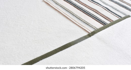 High angle view of three different terry cloth towels folded on top of each other. White, green-bordered, and striped cotton bathroom towels