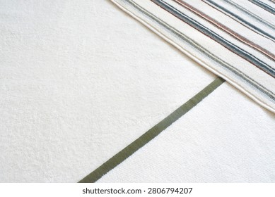 High angle view of three different terry cloth towels folded on top of each other. White, green-bordered, and striped cotton bathroom towels