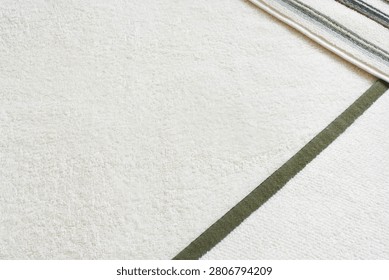 High angle view of three different terry cloth towels folded on top of each other. White, green-bordered, and striped cotton bathroom towels
