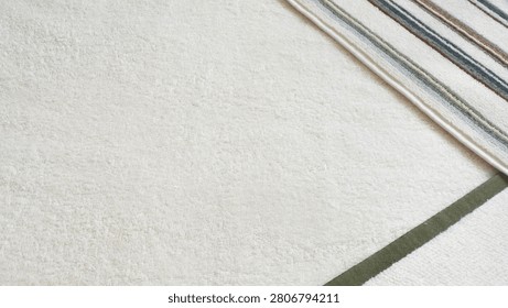 High angle view of three different terry cloth towels folded on top of each other. White, green-bordered, and striped cotton bathroom towels