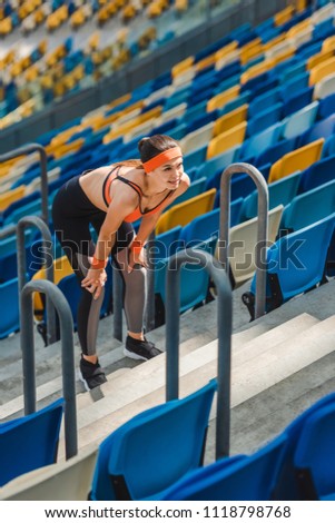 high angle view of tired young woman relaxing on stairs at sports stadium