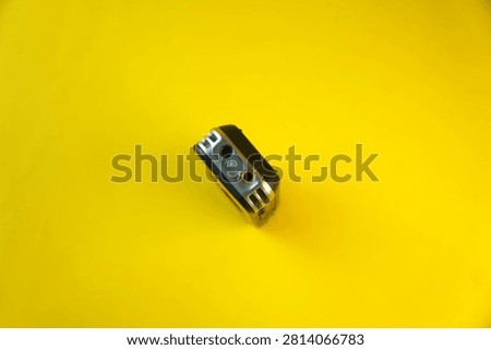 High angle view of the top panel of a digital voice recorder showing a black headphone jack and a red microphone jack input, isolated on a bright yellow background. Concept of audio connectivity, sound hardware, journalism and recording equipment.