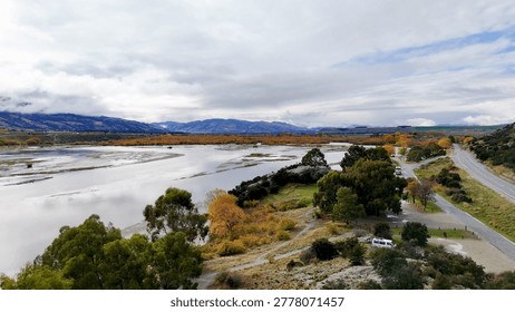 High angle view of a tranquil lakeside road surrounded by autumn trees and mountains.