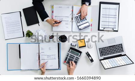 High Angle View Of Two Businesspeople Calculating Bills In Office