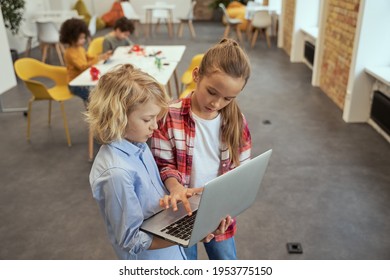 High Angle View Of Two Lovely Kids, Little Boy And Girl Learning, Holding Laptop And Standing In A Classroom During STEM Lesson