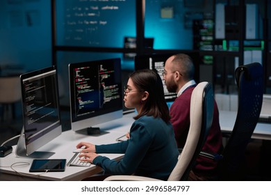 High angle view at two people sitting at workplace in cybersecurity department and writing code in blue lights - Powered by Shutterstock