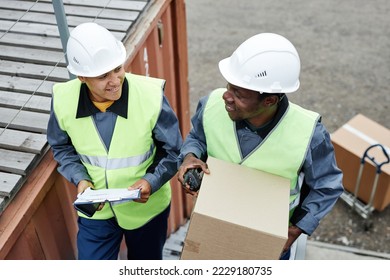 High angle view at two smiling workers carrying boxes up stairs at shipping docks