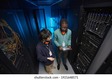 High angle view at two young technicians setting up server network while working in data center, copy space
