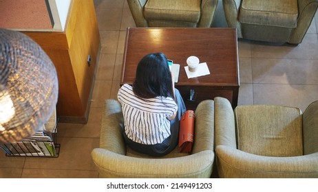 High Angle View Of Unknown Woman Using Laptop And Smartphone On The Table While Sitting In The Cafe