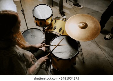 High angle view of unrecognizable female rock musician practicing playing drums, copy space - Powered by Shutterstock