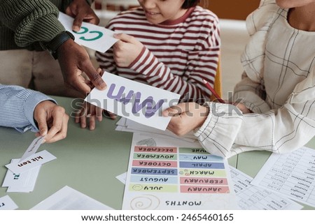 High angle view of unrecognizable foreign language teacher giving printouts to students during lesson