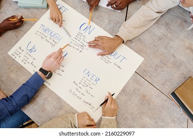 High angle view of unrecognizable group of students learning English phrasal verbs using handmade poster - Shutterstock ID 2160229097