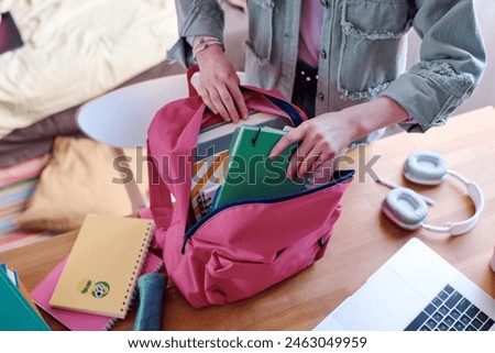 High angle view of unrecognizable student getting ready for school packing her backpack, copy space