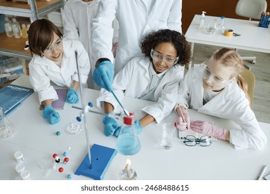 High angle view of unrecognizable teacher and multi-ethnic kids doing experiments in Chemistry class - Powered by Shutterstock