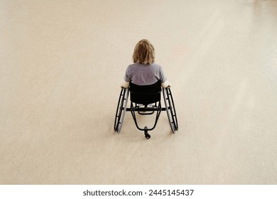 High angle view of unrecognizable young woman in wheelchair dancing alone in spacious studio