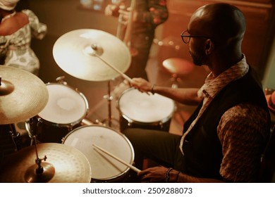 High angle view of unrecognizable young Black man playing drums during jazz concert