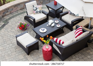 High Angle View Of Upscale Patio Set, Dark Wicker Luxury Furniture With Comfortable Cushions On Outdoor Stone Patio Of Affluent Home