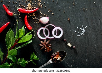 High Angle View of Various Fresh Herbs and Spices, Onion Slices, and Hot Peppers Scattered on Dark Gray Stone Surface with Copy Space - Powered by Shutterstock