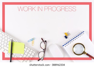 High angle view of various office supplies on desk with a word WORK IN PROGRESS - Powered by Shutterstock