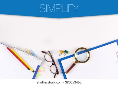 High angle view of various office supplies on desk with a word SIMPLIFY