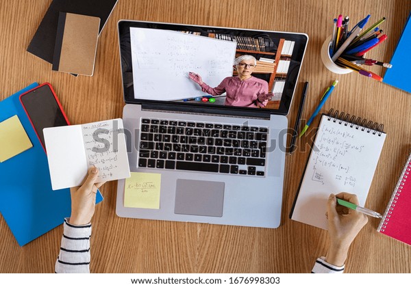 High angle view of video conference with teacher\
on laptop at home. Top view of girl in video call with personal\
tutor on computer listening audio course, distance and e-learning\
education concept.