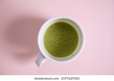 High Angle View Of A White Ceramic Cup With Whipped Matcha Japanese Green Tea, Shot In Studio With Soft Shadow, Isolated On Pink Background With Copy Advertising Space. Flat Lay. Still Life