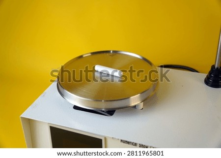 High angle view of a white magnetic stirring bar on a stainless steel hot plate laboratory mixer. Scientific chemistry experiment device for medical research or pharmacy fluid mixing, copy space.