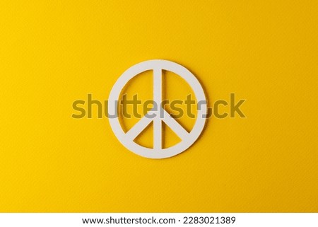 High angle view of white peace sign with copy space on yellow background. Peace and anti war movement concept.