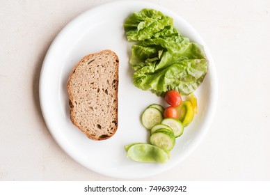 High Angle View Of White Plate With Brown Bread And Healthy Salad Including Lettuce, Tomato And Cucumber On Limestone Background