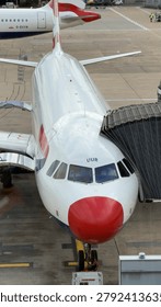 High angle view of a white and red narrow-body aircraft connected to a jet bridge.