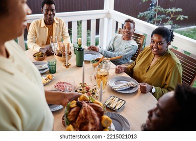 High Angle View Of Woman Bringing Homemade Chicken Dish To Table At Family Dinner Outdoors