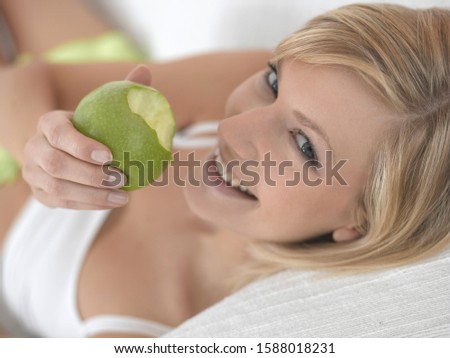 High angle view of woman eating apple on sofa