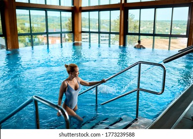 High angle view of a woman getting out of the water after swimming in the pool at the spa. Copy space.