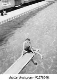 High Angle View Of A Woman Sitting On A Diving Board And Looking Feared