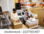 High angle view at workers opening boxes with paper in industrial print shop, copy space
